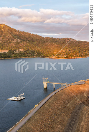 Vertical Aerial view of the Glenbawn Dam wall featuring the water intake system and servicing pontoon in NSW Australia. Drone photograph captures the engineering infrastructure, reservoir waters 140479415