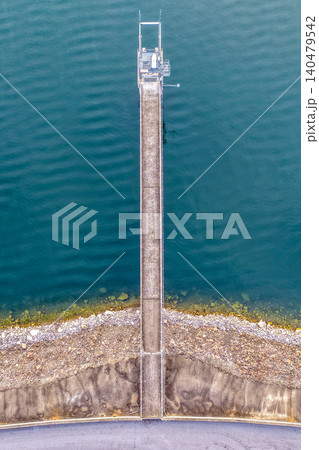 Vertical Aerial downward view of the Glenbawn Dam wall with the walkway leading out to the water intake in NSW Australia. Drone photograph captures the engineering infrastructure, reservoir waters 140479542