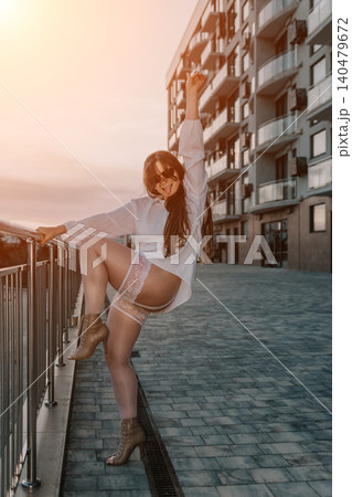 Woman stockings city young playful female posing in white shirt and lingerie on a modern urban walkway during sunset 140479672