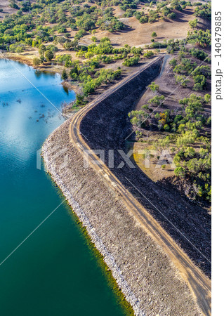 Vertical Aerial view of the access road onto the Glenbawn Dam wall with surrounding landscape in NSW Australia. Drone photograph captures the engineering infrastructure, rugged inland scenery Vertical Aerial view of the access road onto the Glenbawn Dam wall with surrounding landscape in NSW Australia. Drone photograph captures the engineering infrastructure, rugged inland scenery 140479885