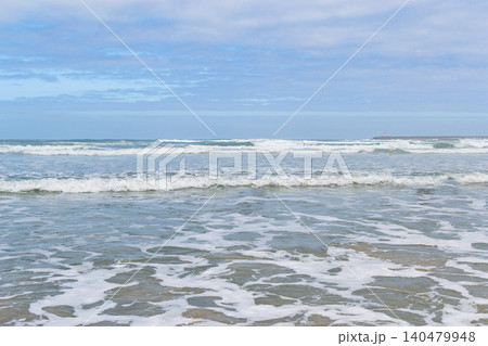 Serene ocean waves crashing gently on a sandy beach under a soft cloudy sky, evoking a peaceful sense of tranquility and freedom. Perfect for travel or wellness designs. Nobody. Serene ocean waves crashing gently on a sandy beach under a soft cloudy sky, evoking a peaceful sense of tranquility and freedom. Perfect for travel or wellness designs. Nobody. 140479948