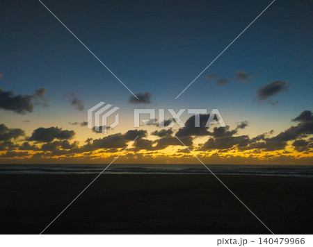 A breathtaking coastal sunset with dramatic dark clouds over the ocean horizon. This scenic view offers a sense of tranquility, perfect for travel themes and atmospheric backgrounds. A breathtaking coastal sunset with dramatic dark clouds over the ocean horizon. This scenic view offers a sense of tranquility, perfect for travel themes and atmospheric backgrounds. 140479966