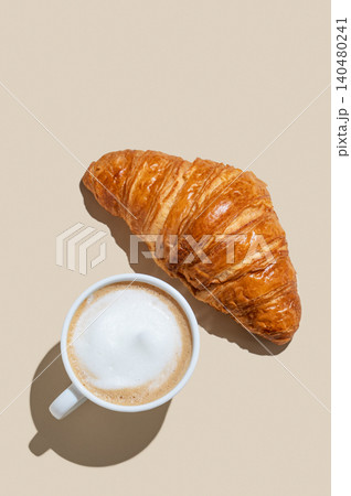 Cup of cappuccino coffee and croissant on a yellow isolated background Cup of cappuccino coffee and croissant on a yellow isolated background 140480241