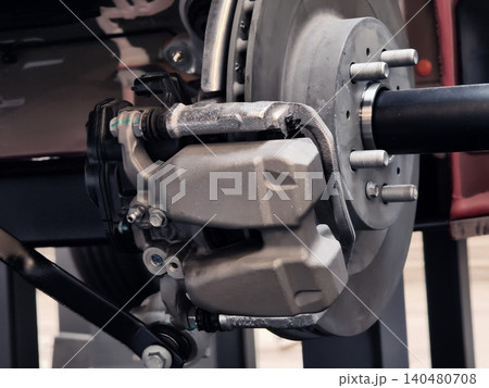 Closeup brake caliper and rotor detail, piston housing, brake pad edges, hydraulic line, metal. Closeup brake caliper and rotor detail, piston housing, brake pad edges, hydraulic line, metal. 140480708