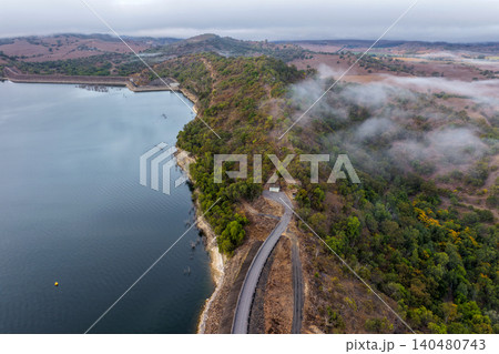 Vertical Aerial image of Glenbawn Dam and the surrounding mountain landscape with morning fog in NSW Australia. Drone photograph captures the expansive reservoir, rugged inland scenery  140480743