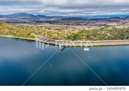 Vertical Aerial view of Glenbawn Dam and the dam wall leading towards the surrounding mountains in NSW Australia. Drone photograph captures the expansive reservoir, rugged inland landscape Vertical Aerial view of Glenbawn Dam and the dam wall leading towards the surrounding mountains in NSW Australia. Drone photograph captures the expansive reservoir, rugged inland landscape 140480976