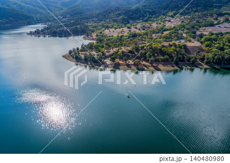 Vertical Aerial view of the Glenbawn Dam boat ramp and surrounding mountains with sunlight reflecting off the water in NSW Australia. Drone photograph captures the expansive reservoir 140480980