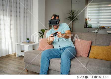 Man playing virtual reality video game at home Man playing virtual reality video game at home 140481158