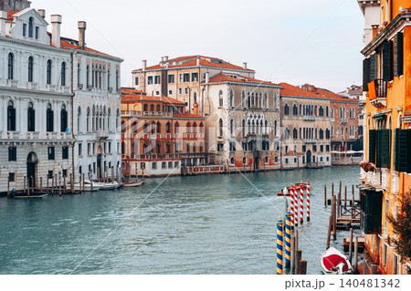Buildings line the canal in Venice with boats docked on the shore in the afternoon light Buildings line the canal in Venice with boats docked on the shore in the afternoon light 140481342