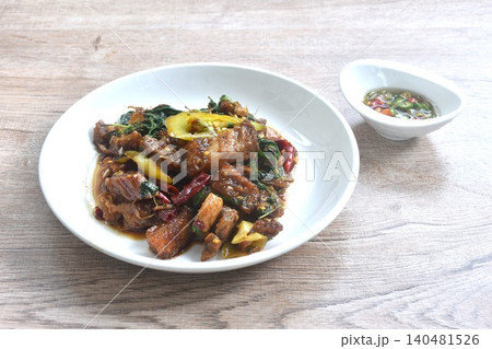 spicy stir fried chop crispy pork with basil leaf on plate dipping slice chili fish sauce spicy stir fried chop crispy pork with basil leaf on plate dipping slice chili fish sauce 140481526