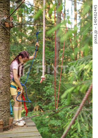 The child attaches a safety rope with a carabiner to descend the route. Sports Training Park The child attaches a safety rope with a carabiner to descend the route. Sports Training Park 140482445
