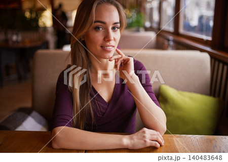 Beautiful blonde woman looking directly at the camera while sitting inside a cozy cafe Beautiful blonde woman looking directly at the camera while sitting inside a cozy cafe 140483648