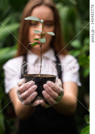 Female gardener holds pot with plant in hands Female gardener holds pot with plant in hands 140483778