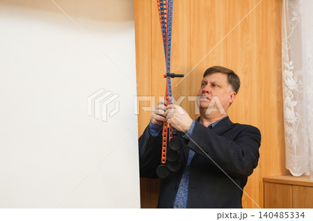 A male photographer lowers a white paper backdrop for a photo shoot in a professional studio 140485334