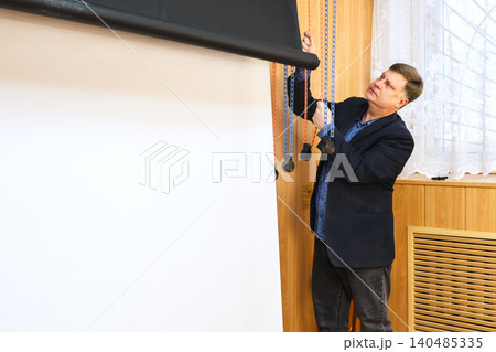 Male photographer lowering a black backdrop for a photo shoot in a professional studio setting 140485335