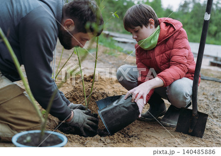 A man and his son plant a dogwood shrub on their countryside property A man and his son plant a dogwood shrub on their countryside property 140485886