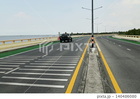 The Chonlamak Witthi Road or Bridge is a beautiful coastal road with a green bicycle lane marked with bicycle symbols on the asphalt road surface. The Chonlamak Witthi Road or Bridge is a beautiful coastal road with a green bicycle lane marked with bicycle symbols on the asphalt road surface. 140486080