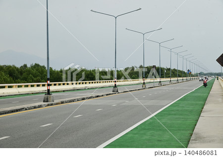 The Chonlamak Witthi Road or Bridge is a beautiful coastal road with a green bicycle lane marked with bicycle symbols on the asphalt road surface. The Chonlamak Witthi Road or Bridge is a beautiful coastal road with a green bicycle lane marked with bicycle symbols on the asphalt road surface. 140486081