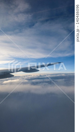 vertical photo of close up of an airplane wing view above clouds with blue sky gradient taken from the jet window, serene high-altitude flight perspective with copy space vertical photo of close up of an airplane wing view above clouds with blue sky gradient taken from the jet window, serene high-altitude flight perspective with copy space 140486096