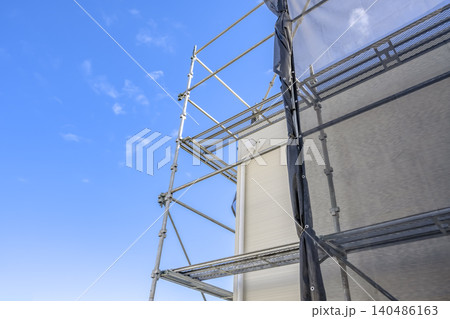 戸建て住宅の屋根リフォーム工事と新しい外壁 足場と青空 140486163