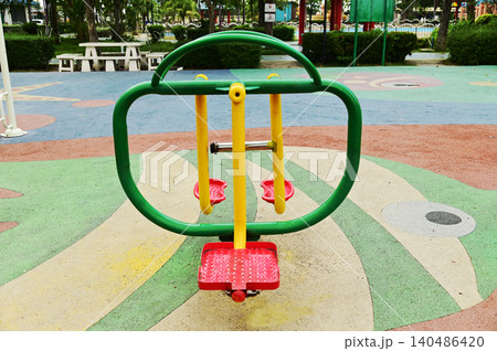 A brightly colored exercise machine. To use it, stand on the platform and swing your legs from left to right. in public parks. A brightly colored exercise machine. To use it, stand on the platform and swing your legs from left to right. in public parks. 140486420