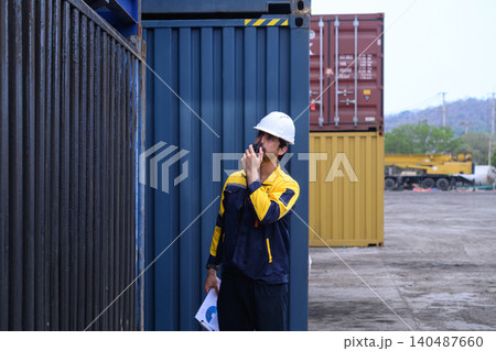 Logistics worker inspecting cargo containers with radio communication at shipping yard Logistics worker inspecting cargo containers with radio communication at shipping yard 140487660