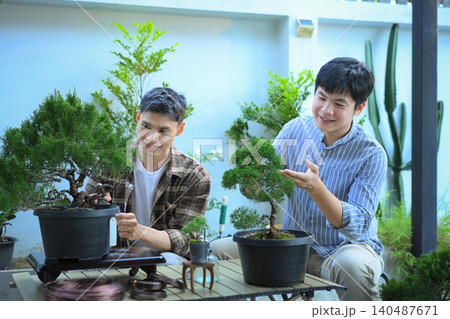 Couple LGBT pruning bonsai together in a peaceful home garden Couple LGBT pruning bonsai together in a peaceful home garden 140487671