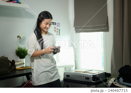 Young Asian Female Student Packing Luggage with Camera Before Moving to University Dorm Room Young Asian Female Student Packing Luggage with Camera Before Moving to University Dorm Room 140487715