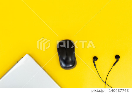 Yellow background with sleek black mouse, earbuds, and laptop keys. Minimalist tech setup for digital creators or students. Modern design evokes focus, calm, and productivity. Perfect for blogs, ads 140487748