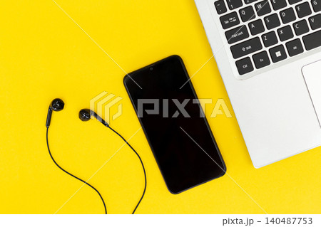 Yellow background with sleek black phone, earbuds, and laptop keys. Minimalist tech setup for digital creators or students. Modern design evokes focus, calm, and productivity. Perfect for blogs, ads Yellow background with sleek black phone, earbuds, and laptop keys. Minimalist tech setup for digital creators or students. Modern design evokes focus, calm, and productivity. Perfect for blogs, ads 140487753