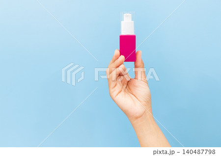 Soft hands hold pink pump bottle. Fingers poised above dispenser, ready to press. Clean background highlights product's simplicity. Ideal for skincare, wellness, or beauty campaigns Soft hands hold pink pump bottle. Fingers poised above dispenser, ready to press. Clean background highlights product's simplicity. Ideal for skincare, wellness, or beauty campaigns 140487798