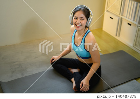 Woman relaxing after workout with headphones, enjoying music and healthy lifestyle at home 140487879
