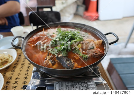 Steaming Fish Hot Pot with Fresh Herbs in Restaurant Setting 140487904