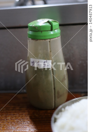Bottle with Green Cap and Rice on Wooden Surface Bottle with Green Cap and Rice on Wooden Surface 140487913
