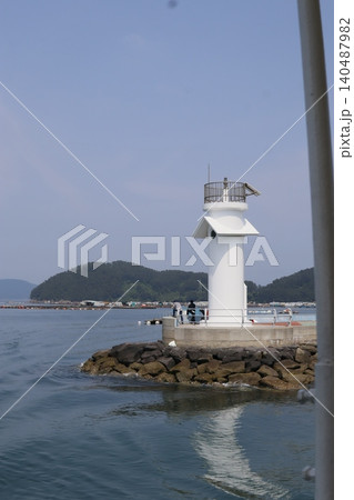 Coastal Lighthouse with Rocky Breakwater and Clear Sky Coastal Lighthouse with Rocky Breakwater and Clear Sky 140487982