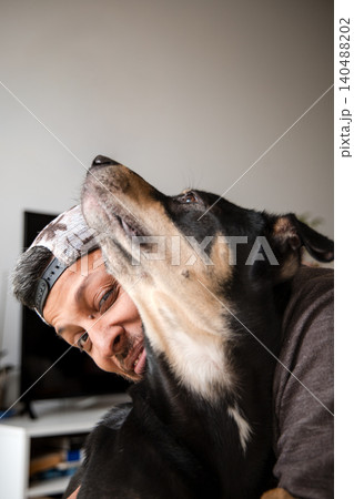 A man is hugging a dog with a brown and black coat 140488202