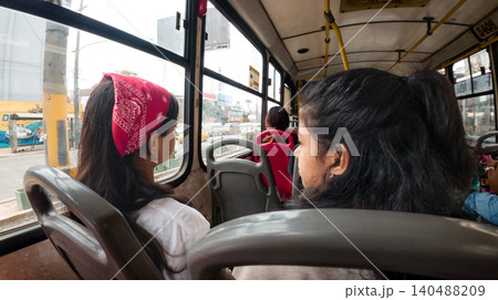 Two teenagers are sitting on a bus, one wearing a bandana Two teenagers are sitting on a bus, one wearing a bandana 140488209