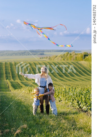 Family flying rainbow kite in a green field Family flying rainbow kite in a green field 140488702
