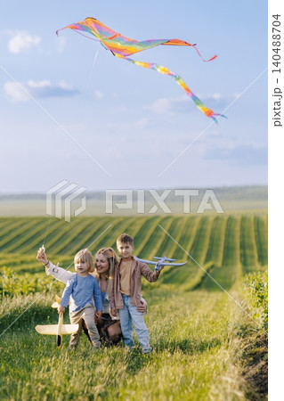Mother and children playing with toys in field 140488704