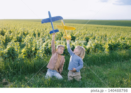 Children playing with toy gliders in green field 140488798