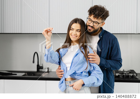 Happy couple holding new house keys in kitchen Happy couple holding new house keys in kitchen 140488872