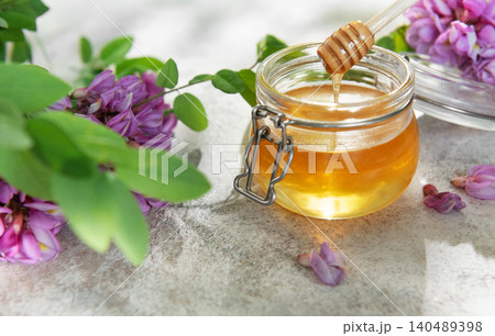 Acacia honey in glass jar with wooden dipper 140489398
