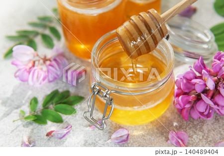 Organic acacia honey dripping from honey dipper 140489404