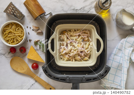 Step 6. Cooking pasta with seafood in creamy cheese sauce, in kitchen gadget modern white air fryer. Lifestyle trendy of new cooking. Step 6. Cooking pasta with seafood in creamy cheese sauce, in kitchen gadget modern white air fryer. Lifestyle trendy of new cooking. 140490782