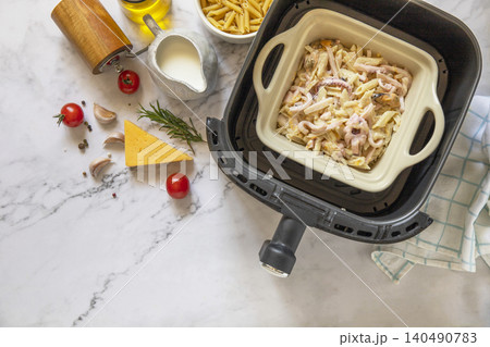 Pasta with seafood in creamy cheese sauce, in kitchen gadget modern white air fryer. Lifestyle trendy of new cooking. Top view flat lay background. Copy space. Pasta with seafood in creamy cheese sauce, in kitchen gadget modern white air fryer. Lifestyle trendy of new cooking. Top view flat lay background. Copy space. 140490783