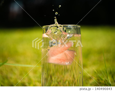 Serving of fizzy lemonade with fruit splashing water in garden Serving of fizzy lemonade with fruit splashing water in garden 140490843