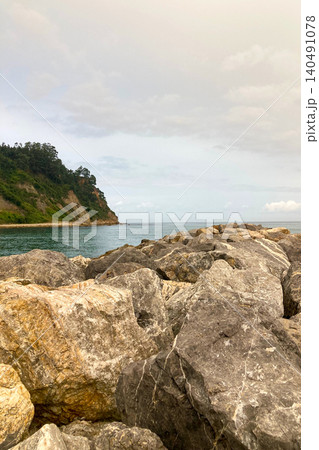 Rodiles Beach in Villaviciosa, Spain, under cloudy weather with soft waves, wet sand, and a calm, moody coastal atmosphere. 140491078