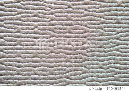 Close-up of quilted mattress texture showing wavy padded pattern on neutral beige fabric surface Close-up of quilted mattress texture showing wavy padded pattern on neutral beige fabric surface 140491544