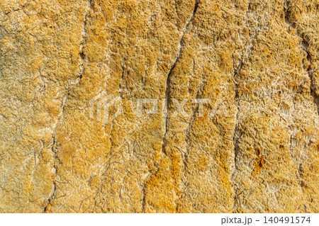 A close-up background of natural stone reveals mineral veins running through its textured surface. A close-up background of natural stone reveals mineral veins running through its textured surface. 140491574
