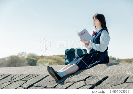 参考書を手に青空の下で学ぶ女子高校生 参考書を手に青空の下で学ぶ女子高校生 140492092